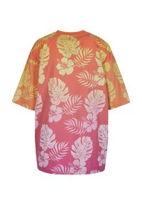 Short-sleeve, oversized t-shirt in coral with a gradient effect. Features white floral and leaf patterns throughout the back and sleeves.