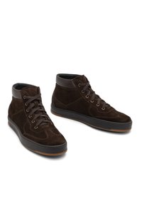 Bottines hautes en suede marron avec une semelle en caoutchouc, dotées d'un design à lacets, d'un col rembourré et de détails de couture subtils.