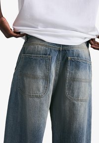 Faded blåa jeans i denim med två stora bakfickor, sydda detaljer och rak benform. Bärs med en enkel vit skjorta.