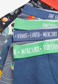 Verschiedene Kinderunterwäsche mit elastischen Taillenbändern in verschiedenen Farben, darunter grün und blau, mit weltraumthematischen Mustern und Text.
