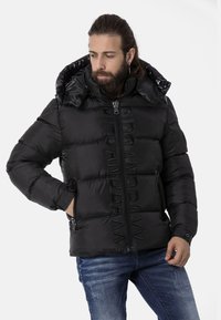 Schwarze Daunenjacke mit hohem Kragen und Reißverschluss. Verfügt über steppartige Abschnitte und Reißverschlussvordertaschen. Glanzende Innenauskleidung der Kapuze.