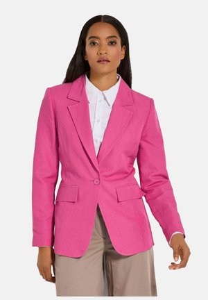 Rosa Blazer im taillierten Schnitt mit einem einzigen Knopf, Reverskragen und zwei vorderen Taschen. Strukturiertes Gewebe, maßgeschneiderte Silhouette, getragen über einem weißen Hemd.