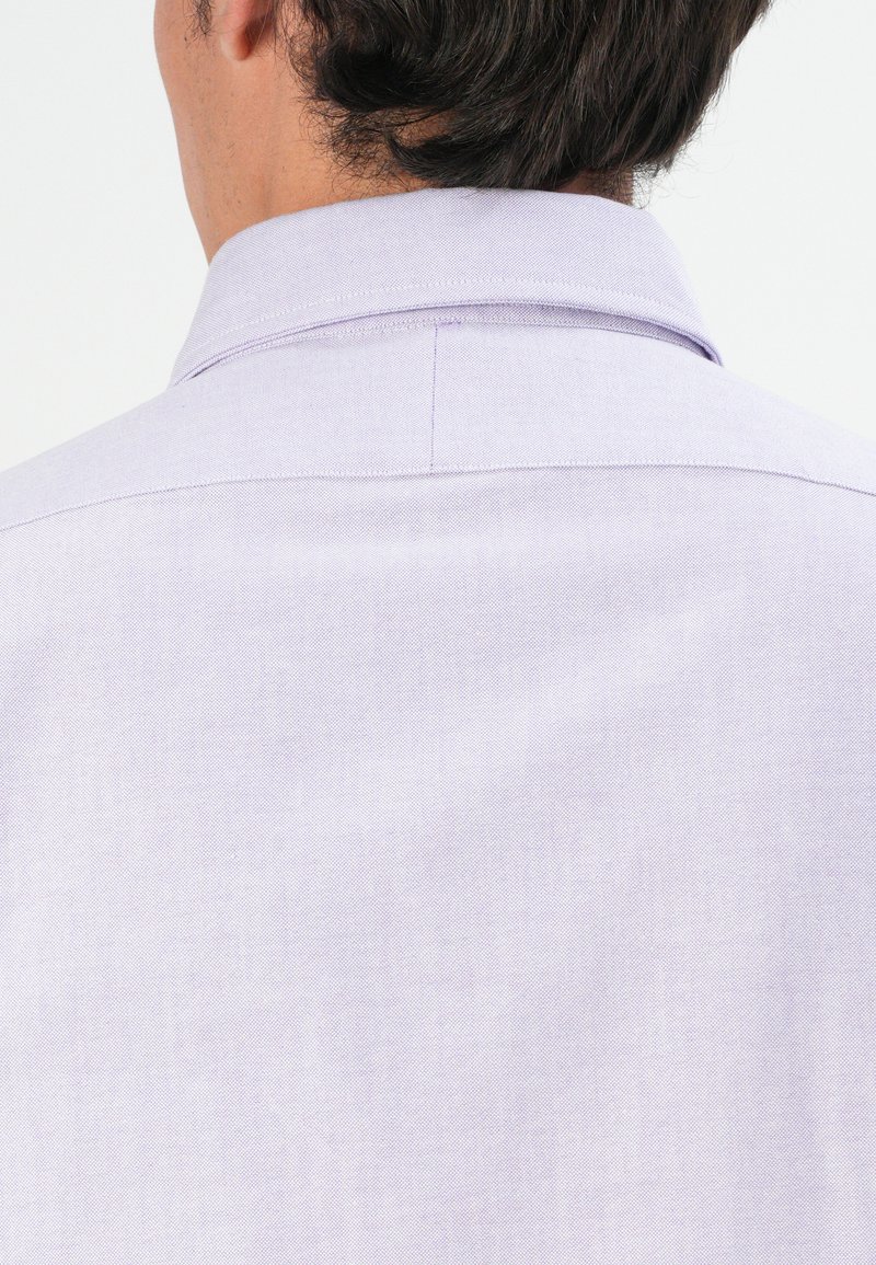 Camisa de color púrpura claro con cuello, hecha de un tejido texturizado, que presenta un diseño limpio en la parte posterior y sutiles detalles de costura.