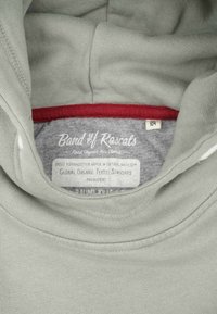 Felpa con cappuccio in cotone organico grigio con fodera interna rossa, caratterizzata da un'etichetta con informazioni sul Global Organic Textile Standard.