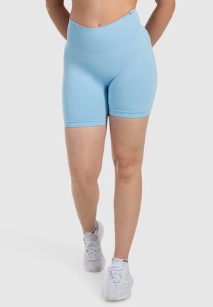 Lichtblauwe stretch high-waisted fietsbroek met een gladde textuur en een knielange snit, gecombineerd met witte sportschoenen.