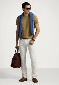 Mala de couro castanho, t-shirt castanha clara, calças brancas, camisola azul em malha pendurada sobre os ombros, óculos de sol, sapatos castanhos e relógio de pulso.