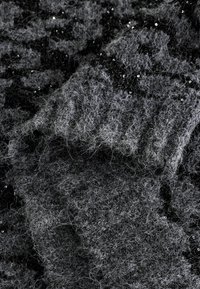 Sivi teksturirani materijal s pahuljastim izgledom, s crnim akcentima i malim šljokicama koje dodaju suptilni sjaj.