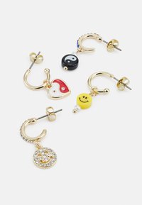 Brincos de argola dourados com vários pendentes: um yin-yang, um coração, uma carinha sorridente e um detalhe em strass. Elementos de design coloridos e divertidos.