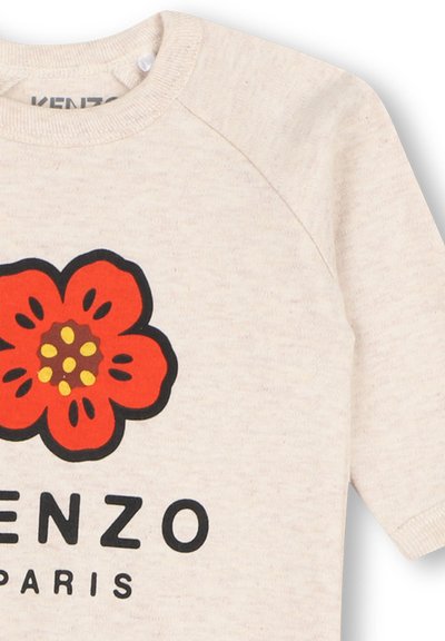 Chemise beige à manches longues avec un graphisme de fleur rouge et le texte noir « KENZO PARIS » sur le devant.