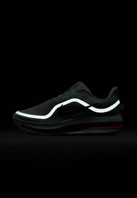 Black athletic shoe with a textured upper, white reflective accents, and a red sole. Features a sleek design and cushioned midsole.
