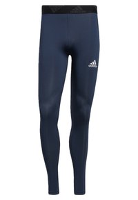 Granatowe legginsy z poliestru o dopasowanym fasonie, z czarnym elastycznym paskiem w talii z logotypem "adidas" oraz białym logo na lewym udzie.