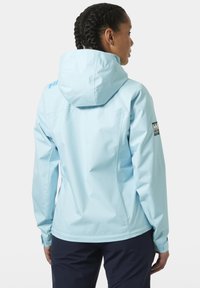Světle modrá nepromokavá bunda s kapucí, s hladkým povrchem, logem na rameni a úzkými rukávy.