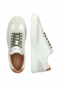 White leather sneakers with suede accents, olive green laces, and tan heel tab. Features perforated detailing and a textured rubber sole.