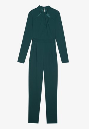 Combinaison à manches longues en tissu vert foncé, avec un col haut, des plis à la taille et une fermeture éclair au dos.