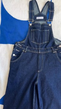 Sötétkék farmer overall ezüst színű hardware-rel. Állítható vállpántokkal, elülső zsebbel és részletes varratokkal a zsebeknél.
