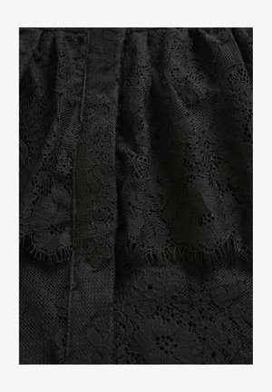 Schwarzer Spitze-Stoff mit komplizierten floralen Mustern, strukturierter Oberfläche und einem geschichteten Design mit fransigen Kanten.