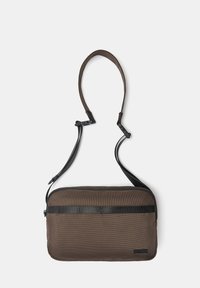 Braune Stoff-Schultertasche mit strukturiertem Oberflächen, schwarzem Gurt und einem horizontalen schwarzen Streifen auf der Vorderseite. Mit einem Reißverschluss versehen.