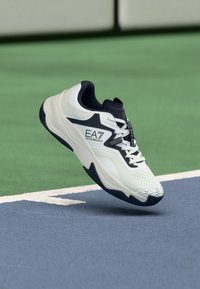 Weißer und marineblauer Sportschuh mit strukturiertem Zehenbereich, gepolsterter Sohle und Logodetail. Verfügt über ein Obermaterial aus Mesh und eine Gummilaufsohle für optimalen Halt.