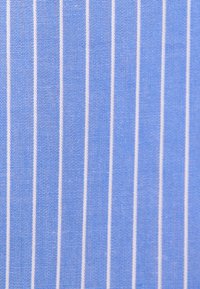 Tissu bleu avec des fines rayures blanches verticales espacées uniformément, montrant une texture tissée détaillée.