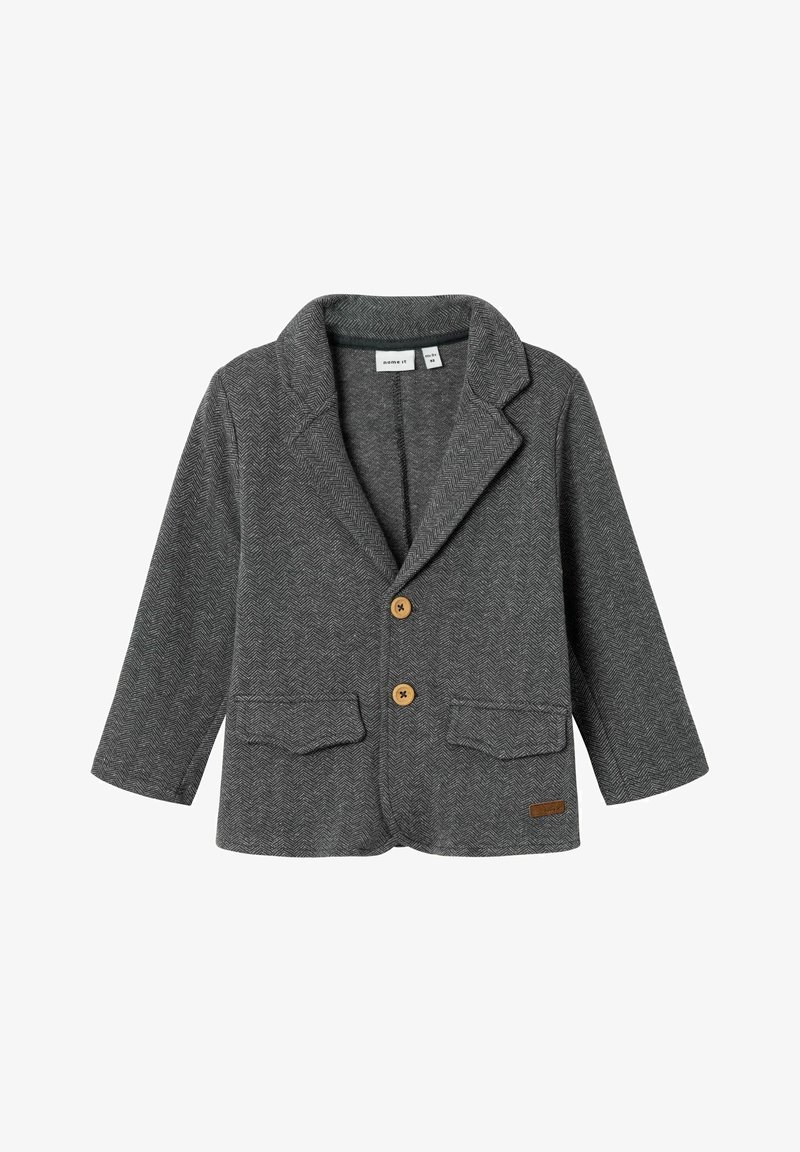 Šedý sako v herringbone vzoru s klopovým límcem, dvěma předními kapsami, hnědými knoflíky a malou koženou štítkou na dolním pravém boku.