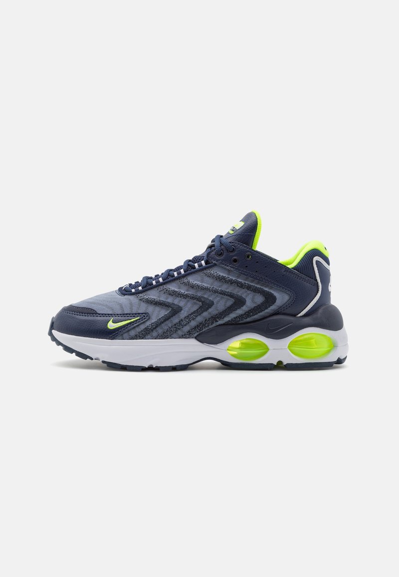 Navy athletic shoe with mesh and synthetic material, zigzag pattern, lime green accents, cushioned sole, and white midsole.