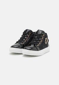 Zapatillas altas de charol negras con detalles de hardware dorado, panel lateral texturizado, suela de goma blanca y cordones negros.