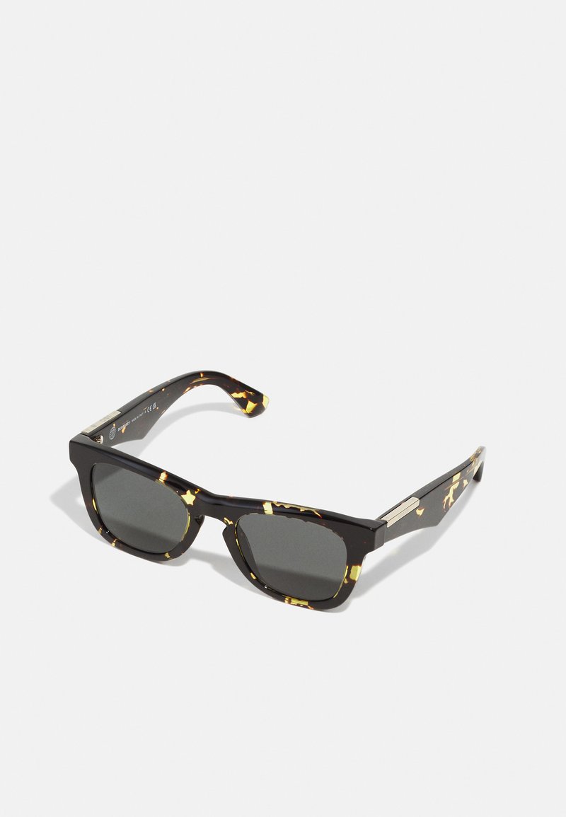 Ochelari de soare negri cu un model scoică, lentile rectangulare și accente metalice, prezentând o finisare lucioasă și brate rezistente.