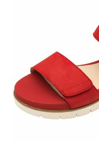 Sandal in suede rosso con una larga cintura regolabile, punta arrotondata e suola in gomma bianca, caratterizzata da dettagli cuciti per un tocco in più.