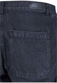 Jeans de mezclilla oscura con detalle en el bolsillo trasero y una superficie texturizada. Incluye una etiqueta que dice "URBAN CLASSICS" en la cinturilla.