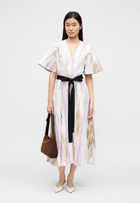 Maksi obleka z zvončastimi rokavi v pastelnih barvah s črtastim vzorcem, poudarjena s črnim pasom. Zraven rjava torbica in bež čevlji.