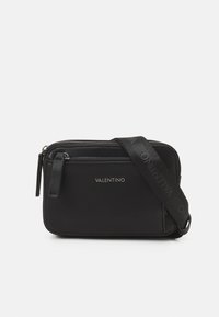 Borsa a tracolla nera in materiale sintetico testurizzato, con doppi zip, dettaglio del logo e tracolla regolabile con il nome del marchio. Design compatto e rettangolare.
