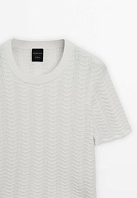 Top en maille blanc à manches courtes avec texture motif vague et encolure ronde, étiqueté Massimo Dutti Studio.