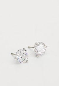 Round stud earrings feature clear, faceted crystal stones set in four-prong silver-tone metal settings, showcasing a polished finish.