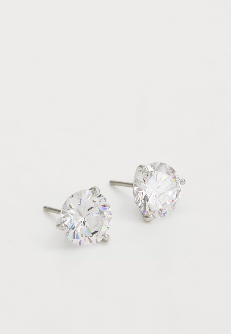 Round stud earrings feature clear, faceted crystal stones set in four-prong silver-tone metal settings, showcasing a polished finish.