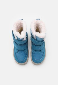 Par af blå vinterstøvler med beige såler og lyserød faux fur-foring, fastgjort med to brede velcro-stropper på hver støvle.