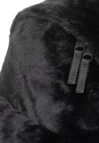 Schwarzer Kunstfell-Rucksack mit glatter Textur, subtiler Glanz und zwei strukturierten Reißverschluss-Zippern für sicheren Verschluss.