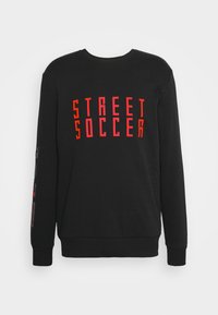 Sort sweatshirt lavet af bomuldsblanding med fed rød "STREET SOCCER" tekst på forsiden og grafiske detaljer på ærmerne. Lange ærmer, ribkantede manchetter.