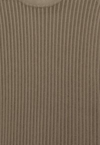 Tissu tricoté côtelé beige avec des rayures verticales texturées et un col rond, montrant des motifs de couture détaillés.