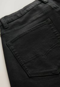 Zwarte denim jeans met een patchezak en subtiele stikdetails. De stof is glad met een lichte textuur en toont een strak ontwerp.