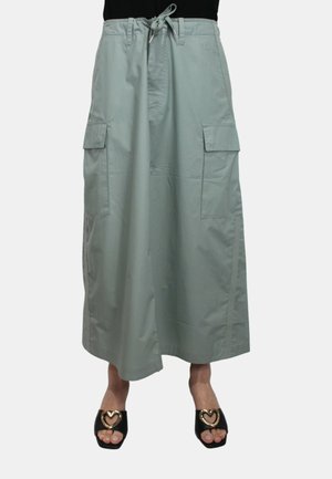 Pantaloni cargo larghi di colore verde chiaro con vita regolabile con cordino, tasche laterali e una texture liscia, abbinati a sandali neri con accenti a forma di cuore.