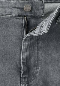 Grijze denim jeans met een ongeopende rits aan de voorkant en een knop met het label "MNG DENIM" boven de rits.