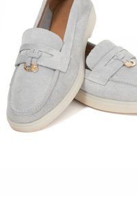 Grey suede loafers with a low profile, featuring a decorative bow and gold hardware accents on the front. Textured surface and soft lining.