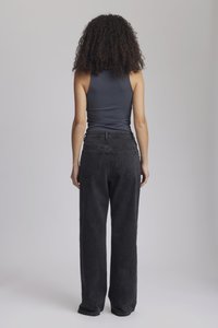 Mørkegrå, høyt liv vide jeans med to baklommer. Modellen har på seg en tettsittende grå tanktopp, sett fra bak.