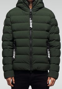 Zelená péřová bunda s kapucí, vybavená předním zipem, prošívaným designem a logo akcenty na zipu a rukávech.