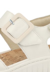 White leather sandal featuring a chunky heel, a large square buckle, and a textured cork insole. Accents include contrasting stitching.