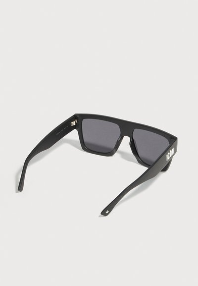 Μαύρα ορθογώνια γυαλιά ηλίου με σκοτεινούς φακούς και το κείμενο «ICON» σε λευκό στην δεξιά πλευρά του βραχίονα, εμφανιζόμενα σε απλό ανοιχτό φόντο.