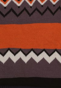 Gebreide trui van stof met oranje, paarse en zwarte zigzagpatronen. De textuur is zacht met duidelijke horizontale strepen.