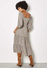 Florales Midikleid mit quadratischem Ausschnitt, Puffärmeln und mehrstufigem Rock; verfügt über einen grünen Untergrund mit kleinen rosa und weißen Blumen.