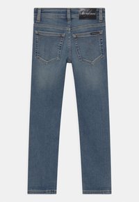 Modré džínové kalhoty s rovnými nohavicemi, obsahující dvě zadní kapsy s jemným prohnutým švem a štítkem na pase.