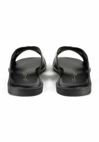 Sandali piatti neri con due ampie cinghie, finitura in pelle liscia, punta arrotondata e suola testurizzata per una migliore aderenza. Design minimalista con branding in oro.